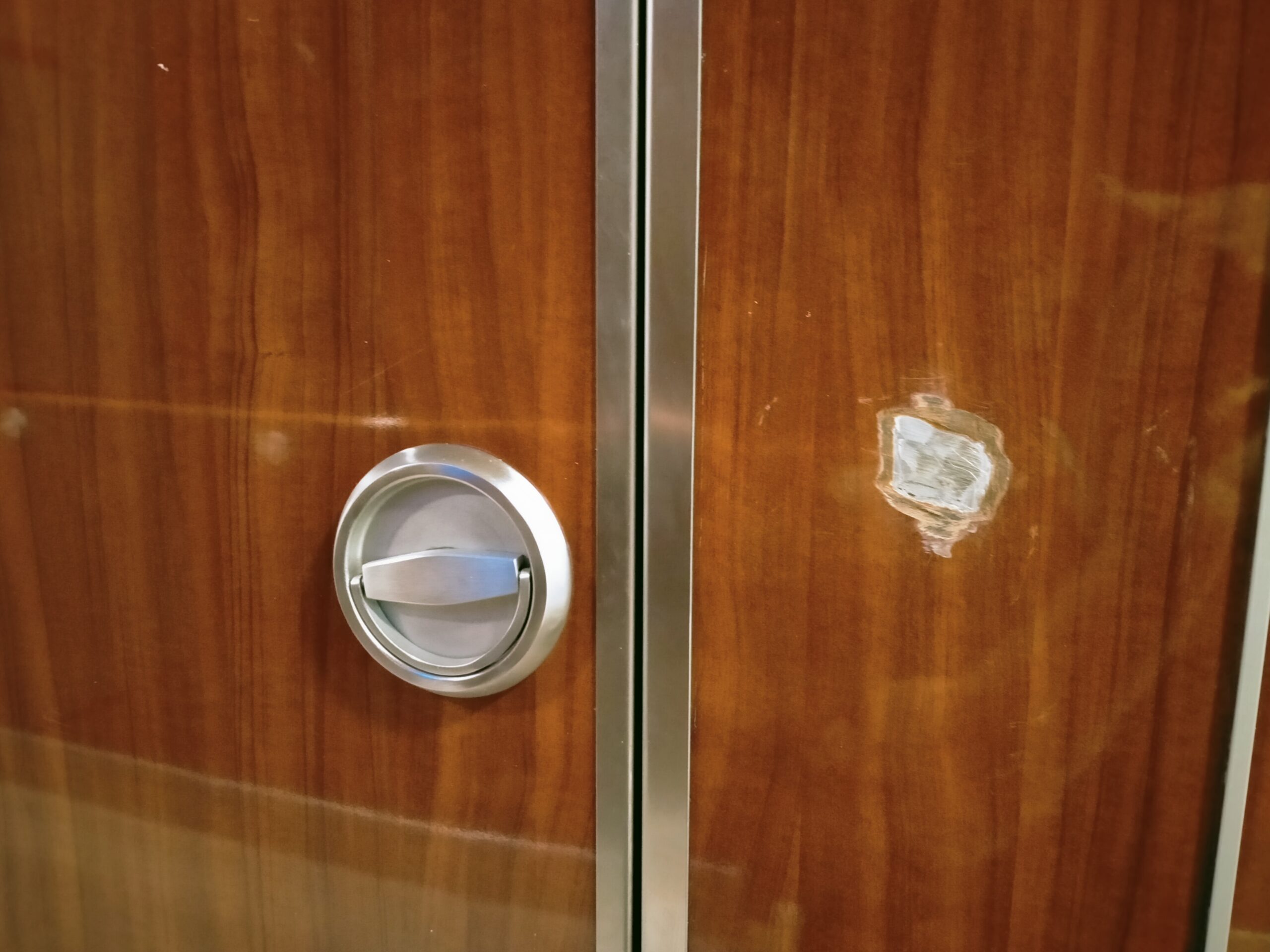 Laminat na ścianie koloru cherry w wysokim połysku z dużą dziurą